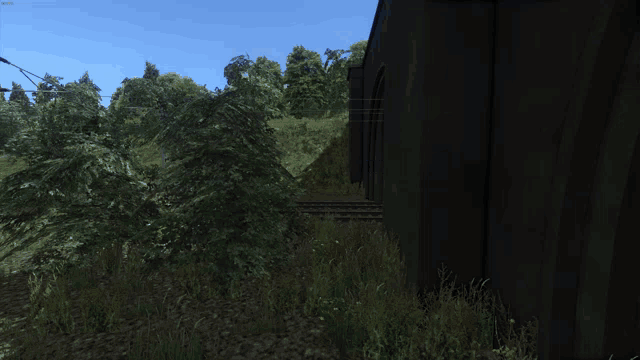 a blue train is parked in a grassy area next to a building