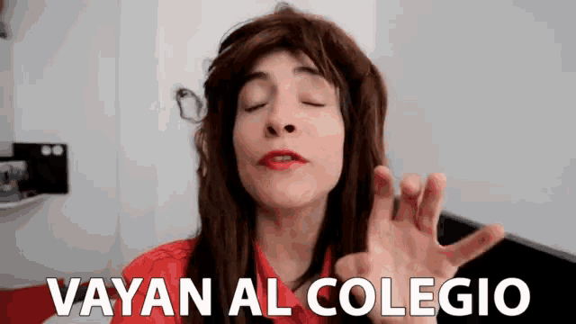 a woman in a red shirt says " vayan al colegio " in white letters