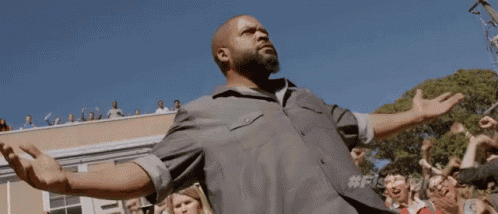 a man with his arms outstretched standing in front of a crowd of people .