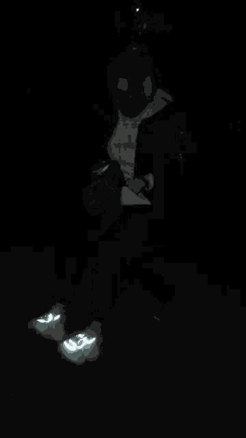 a person wearing glow in the dark shoes sits in a dark room