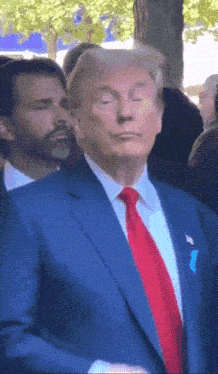 a man in a blue suit and red tie is standing in a crowd