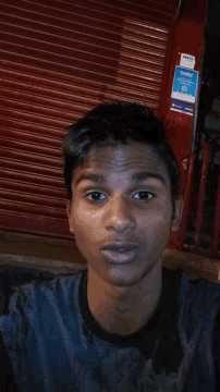 a young man stands in front of a red shutter with a sign on it that says ' aa ' on it