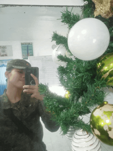 a soldier is taking a picture of himself in front of a christmas tree