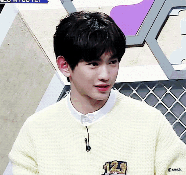 a young man wearing a yellow sweater with the number 123 on the front