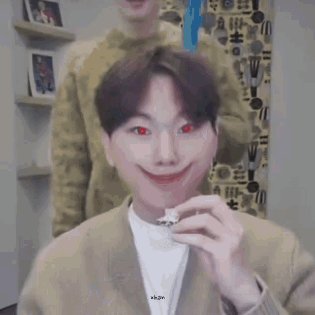a man with red eyes is holding a piece of food in his hand and making a funny face .