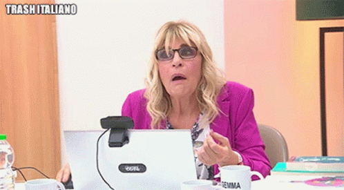 a woman wearing glasses is sitting at a desk in front of a laptop computer .