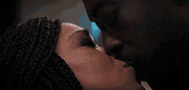 a man and a woman are kissing and the woman has braids on her head