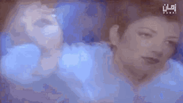 a close up of a woman 's face in a blurry photo with a blue background .