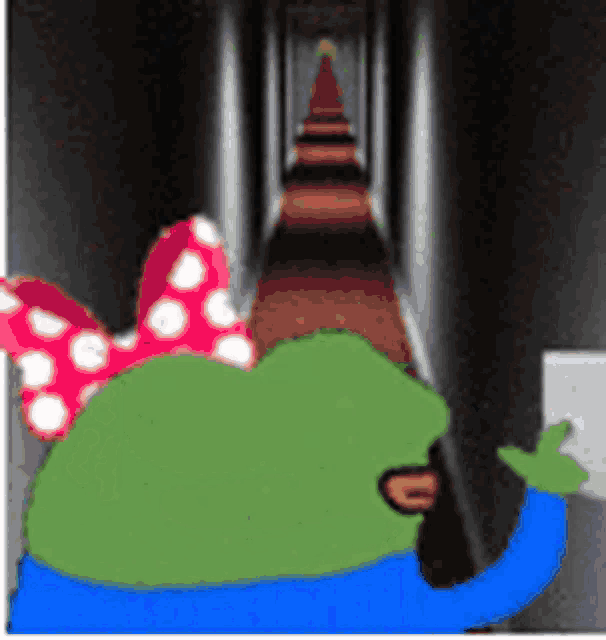 a green frog with a red and white bow on his head is standing in a hallway .