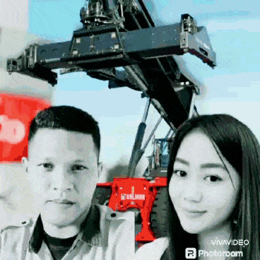 a man and a woman are posing for a picture in front of a large crane ..