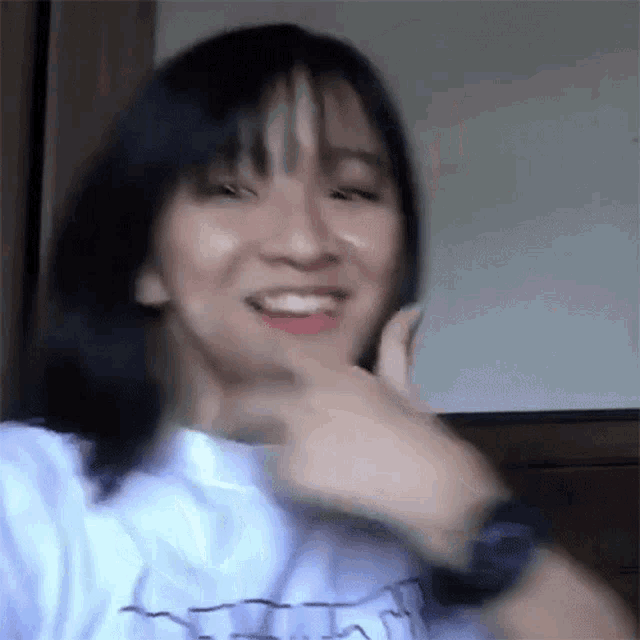a woman wearing a watch and a white shirt is making a funny face .