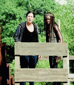 a man and a woman are standing behind a wooden railing