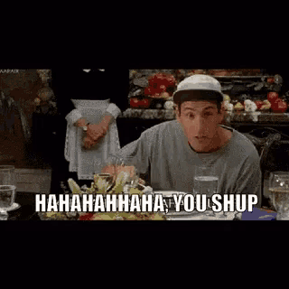 a man is sitting at a table with a knife in his mouth and the words ' hahahaha you shup ' on the screen