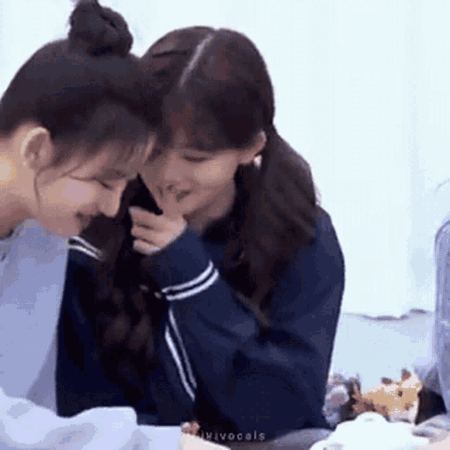 a couple of girls are sitting next to each other at a table .