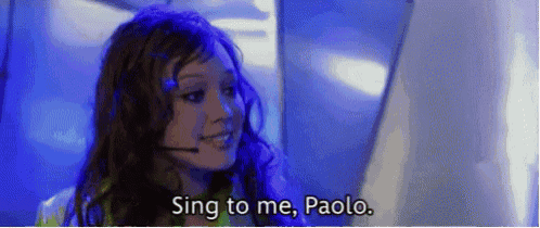 a woman wearing a headset is singing to a man .
