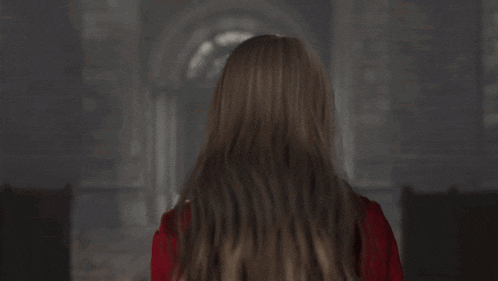 a woman in a red jacket and choker looks at the camera