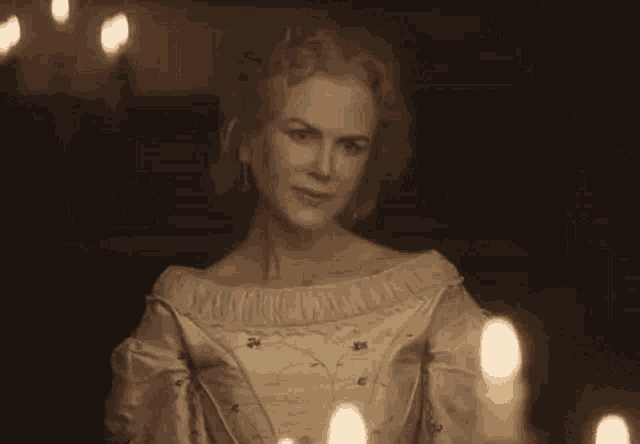 a woman in a white dress is sitting in front of candles .