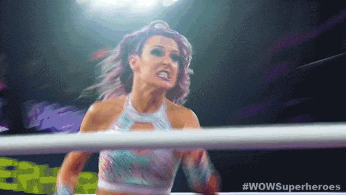 a woman with purple hair is in a wrestling ring with the words wowsuperheroes on the bottom
