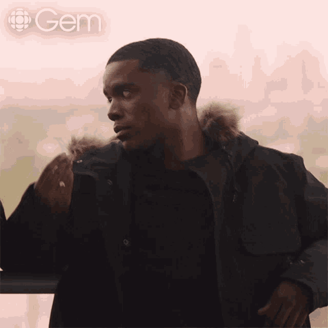 a man in a black jacket is smoking a cigarette with the gem logo behind him