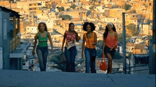 a group of women are walking down a hill in a slum area