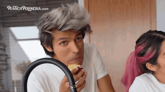 a man with gray hair eating an apple next to a woman with pink hair and a website called platica polinesia.com