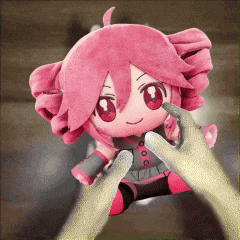 a person is holding a pink stuffed doll in their hands