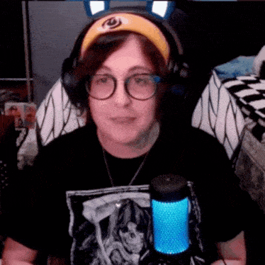 a woman wearing glasses and a headband is sitting in front of a microphone