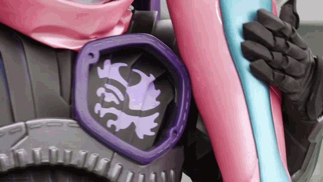 a person wearing a pink and blue costume with a purple emblem on it