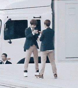 two men in suits are standing next to each other holding hands in front of a white truck .