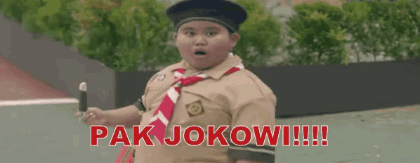 a boy in a school uniform is holding a stick and the words pak jokowi !!! are written above him .