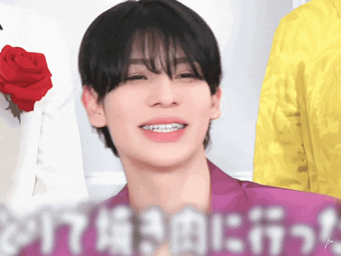 a man with braces on his teeth is smiling in front of a sign that says ' i love you '