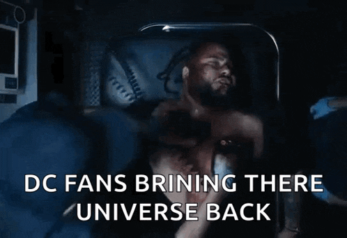 a man is laying in a hospital bed with the words " dc fans brining there universe back "