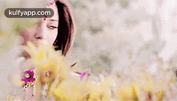 a woman is standing in front of a bunch of flowers and looking at the camera .