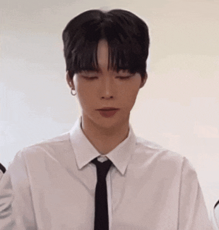 a young man wearing a white shirt and black tie is looking at the camera with his eyes closed .