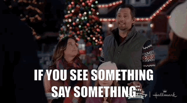 a family is standing in front of a christmas tree with the words if you see something say something on the bottom