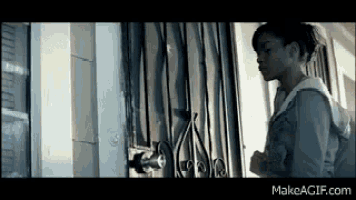 a young girl is standing in front of a door with a lock on it .