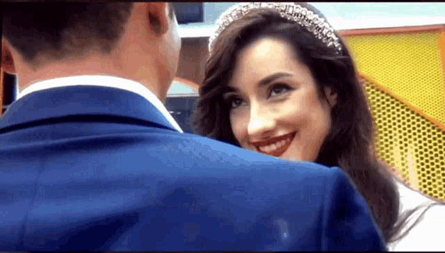 a man in a suit and a woman in a wedding dress are smiling at each other