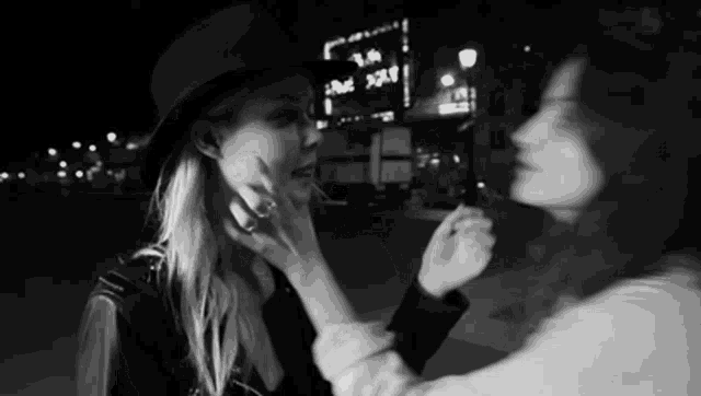 a woman touches another woman 's face in front of a sign that says rue x