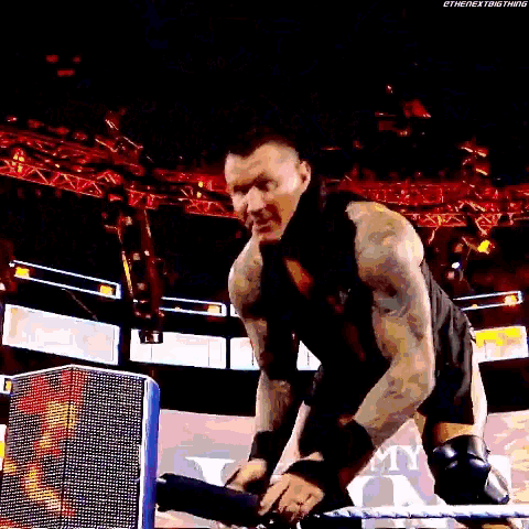 a wrestler is kneeling down in a wrestling ring and holding a microphone .