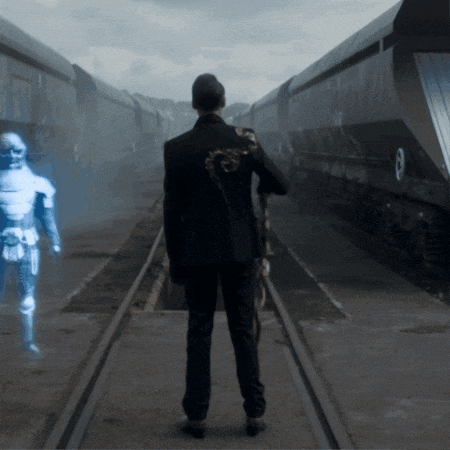 a man in a suit is standing on a train track with a robot behind him