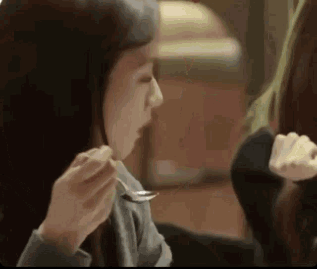 a woman is holding a spoon in her mouth while eating food .