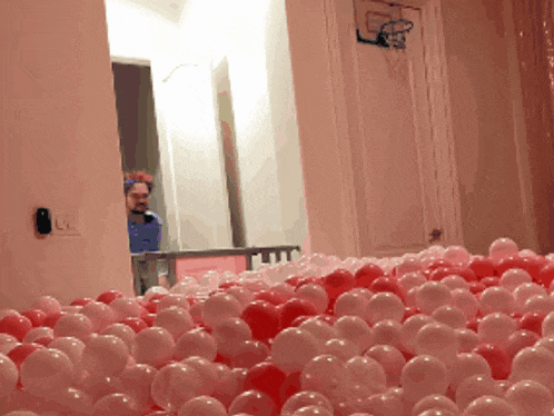 a man is standing in a room filled with red and white balls