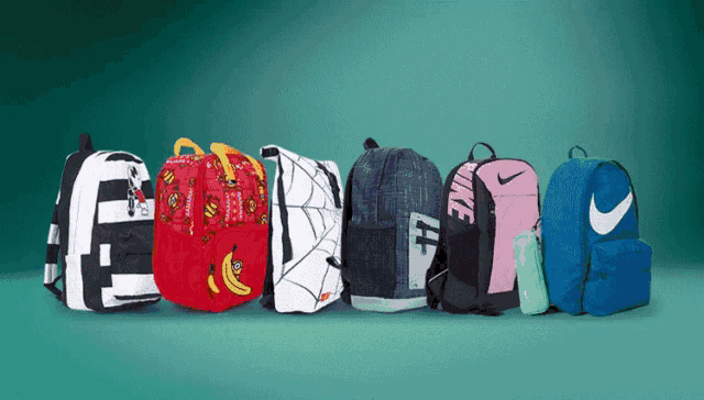 a bunch of nike backpacks are lined up on a green background