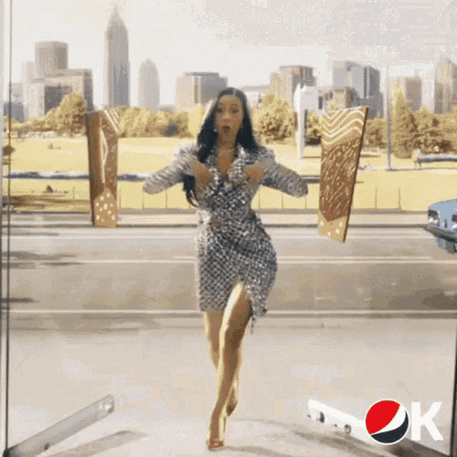 a woman in a dress is standing in front of a pepsi sign .