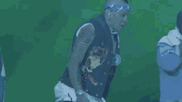 a man wearing a bandana is holding a microphone in his hand