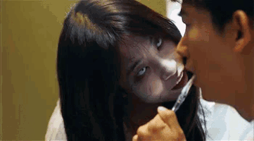 a man is brushing his teeth with a toothbrush while a woman with a knife in her mouth looks on .