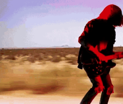 a person playing a guitar in the desert with a mountain in the background
