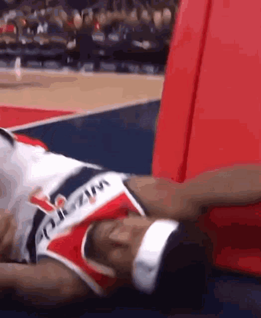 a basketball player is laying on the floor with his head on a cushion .