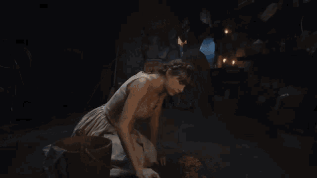 a woman in a white dress is kneeling on the floor in a dark room .