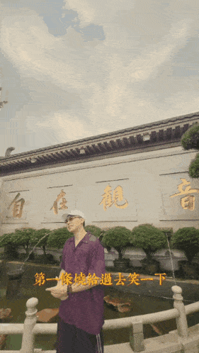 a man in a purple shirt is standing in front of a building with chinese writing on it